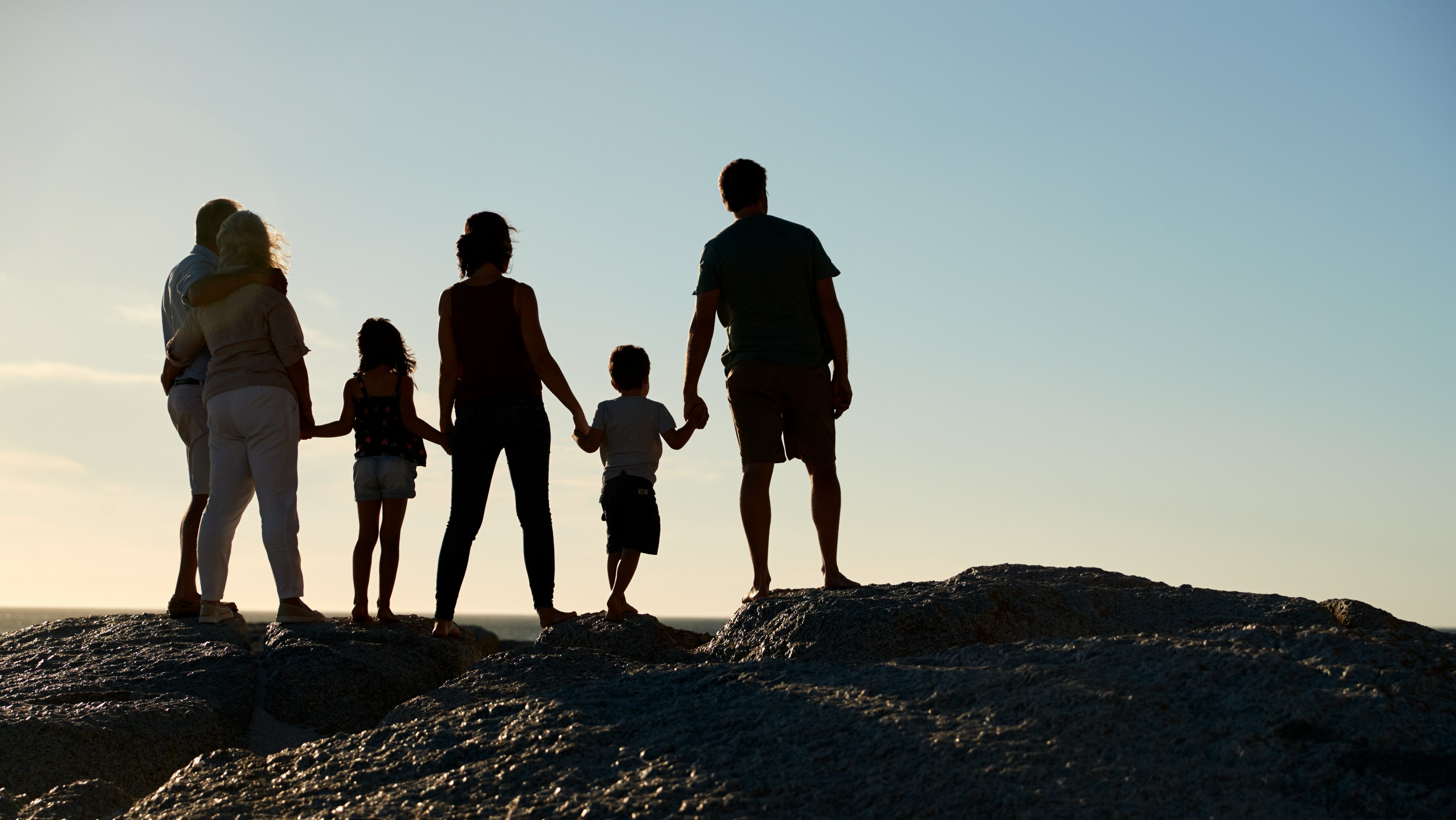 Three,Generation,Family,On,A,Beach,Holding,Hands,,Admiring,View,